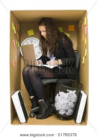Businesswoman in a very small Cardboard Office isolated on white background