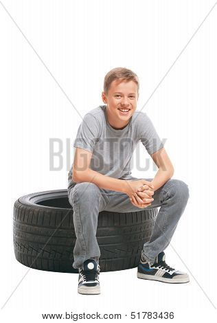 Smiling teenager sitting on a car tire