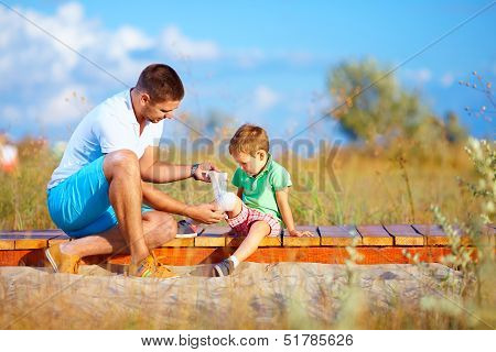Father Bandaging Injured Leg Of Kid