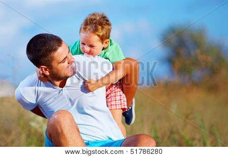 Father And Son Having Fun Playing At Summer Field