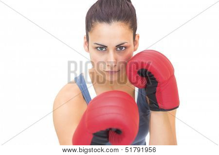 Attractive sporty brunette wearing red boxing gloves on white background