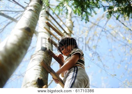 Happy kid having fun climbing on ladder in forest cabin