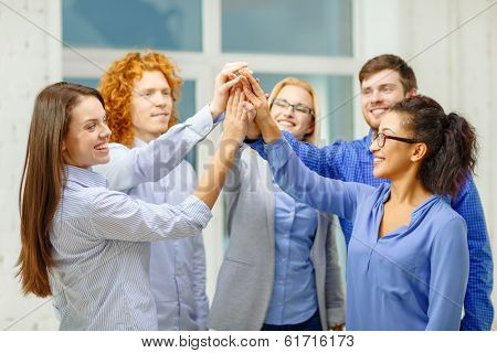 business, office, gesture and startup concept - smiling creative team doing high five gesture in office