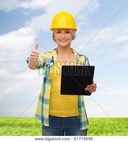 repair, construction and maintenance concept - smiling woman in helmet with clipboard showing thumbs up
