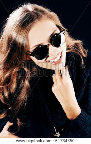 Close-up portrait of a smiling young lady with beautiful hair wearing black sunglasss.