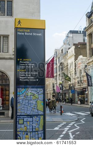 LONDON, UK - MARCH 01: Direction signs post in Mayfair, with famous shop banners and pedestrians passing by in the background. March 01, 2014 in London.