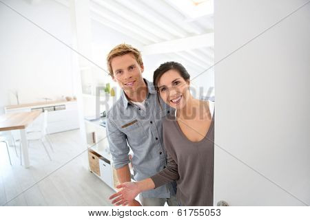 Young couple inviting people to come in new place