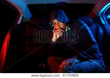 Man in the backseat of a car wearing a hoodie shirt