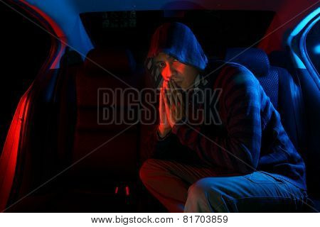 Man in the backseat of a car wearing a hoodie shirt