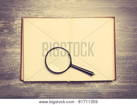 Book And Loupe On Wooden Table.