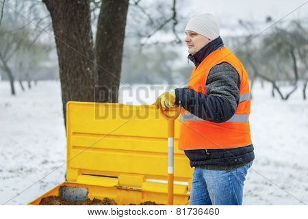 Worker with snow shovel in winter