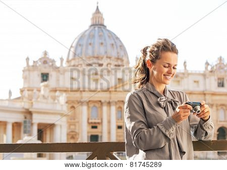 Happy Young Woman Checking Photos In Camera In Front Of Basilica