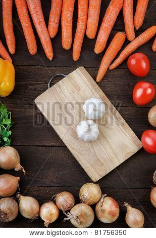 Garlic on the cutting board with vegetables mix on the table