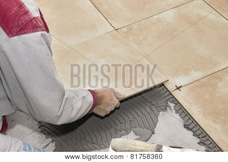 Home improvement, renovation - construction worker tiler is tiling ceramic tile floor.