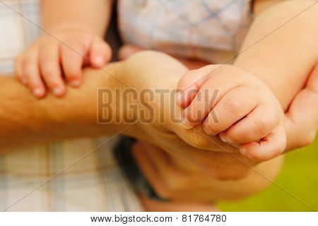 A parent holds the hand of a small child