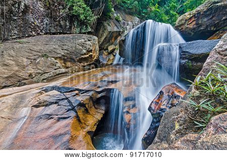 Jungle waterfall with flowing water, large rocks