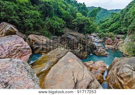 Jungle waterfall with flowing water, large rocks