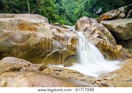 Jungle waterfall with flowing water, large rocks