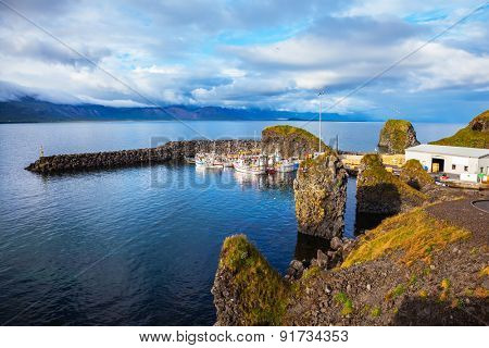Sunset on the fjord in Iceland. White fishing boat in the harbor pier village Arnastapi