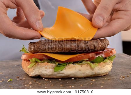 Cook preparing cheese burger.