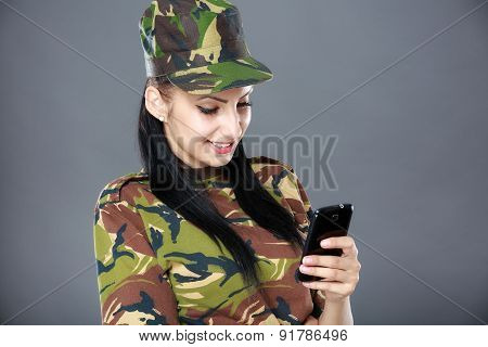 happy woman soldier looks at a mobile phone