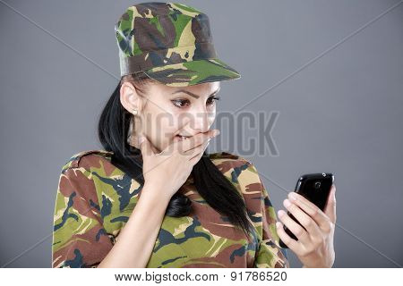 happy woman soldier looks at a mobile phone