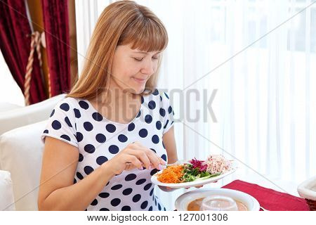 Beautiful young woman sitting at the breakfast table with a plate in his hand in cafes and eating