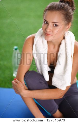 Beautiful young woman relaxing after exerscises on the grass