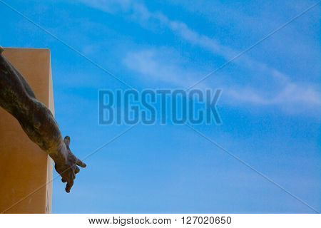 A bronze hand pointing a blue summer sky