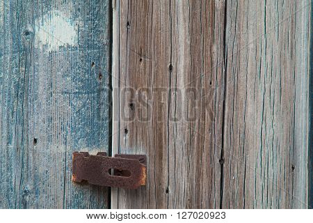 Weathered grey and cyan window with his rusty lock