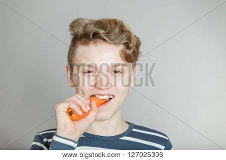 Fun Young Boy Biting Into A Fresh Raw Carrot