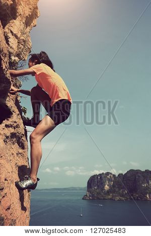 young woman rock climber climbing at seaside mountain rock