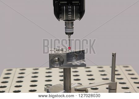 Detail of the tip of a 3d laser scanner mechanical arm with laser beam scanning a surface.
