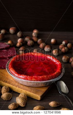 Fresh strawberry pie with nuts on side and frozen berries. Strawberry cake on dark table. Dark and moody style. Magic moon and mistic light