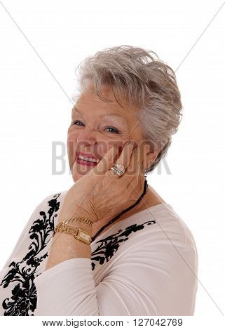 A lovely senior woman in her seventies holding her hand on her face and smiling isolated for white background.