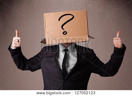 Businessman standing and gesturing with a cardboard box on his head with question mark