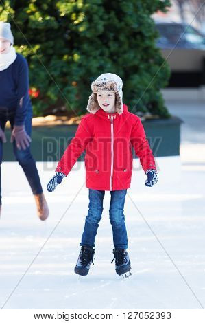 smiling positive boy enjoying ice skating at outdoor skating rink winter holiday or vacation activity