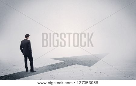 A professional businessman thinking while standing on a black arrow pointing forward in grey space concept