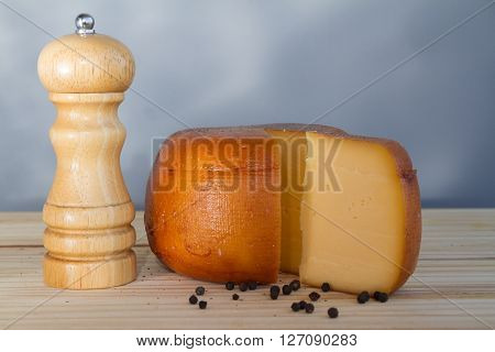 Cheese Wheel And Slice With Wooden Peppermill With Peppercorns
