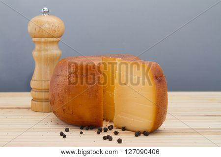 Cheese Wheel And Slice With Wooden Peppermill With Peppercorns