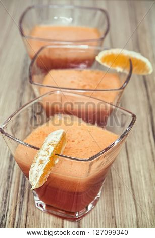 Three portions of refreshing smoothie with orange slices on the wooden background. Healthy lifestyle. Drinks theme.
