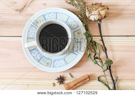 Black coffee and dried rose on wooden palette background