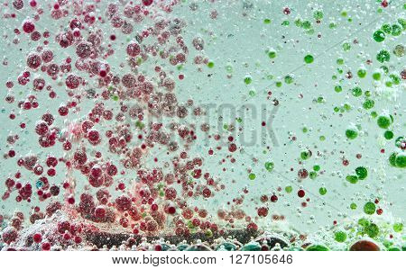 Bright and colorful multi-colored liquid in motion. Lava lamp with green, yellow, blue, purple flowers. Movement of ink of different colors in the oil, background