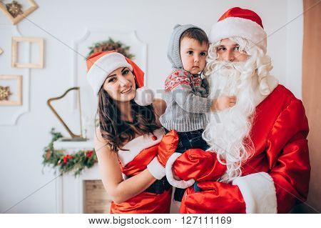 Beautiful family with baby boy under the Christmas tree