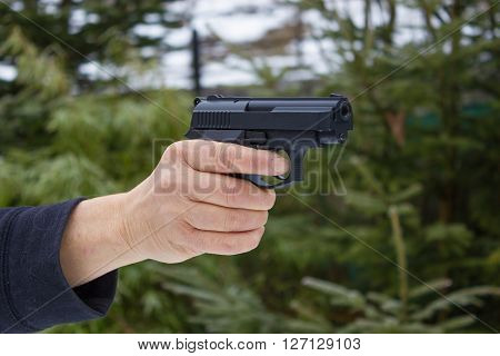 Woman shooting outdoor with a gun selective focus after shoot the Pistol.