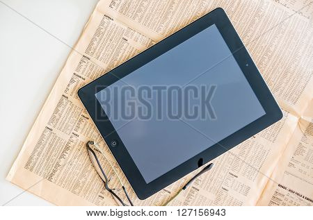 LONDON UNITED KINGDOM - MARCH 20 2014: Modern iPad Tablet computer above the Financial Times magazine with worldwide stock exchange quotations and prices - next to modern vision eye wear glasses