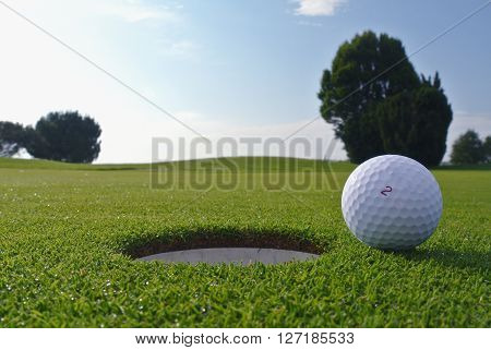 a golf ball near a hole and a beautiful blue sky