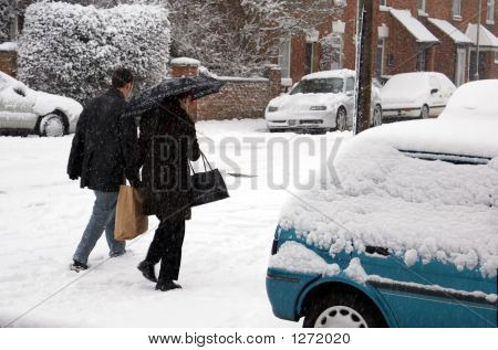 Um casal caminhando na neve carregando sacolas