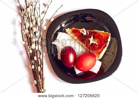 Stylish black plate with piece of cake twigs of willow and Easter eggs isolated white background