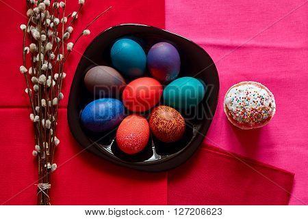Festive Easter table in red colour with colorful eggs cake and willow twigs